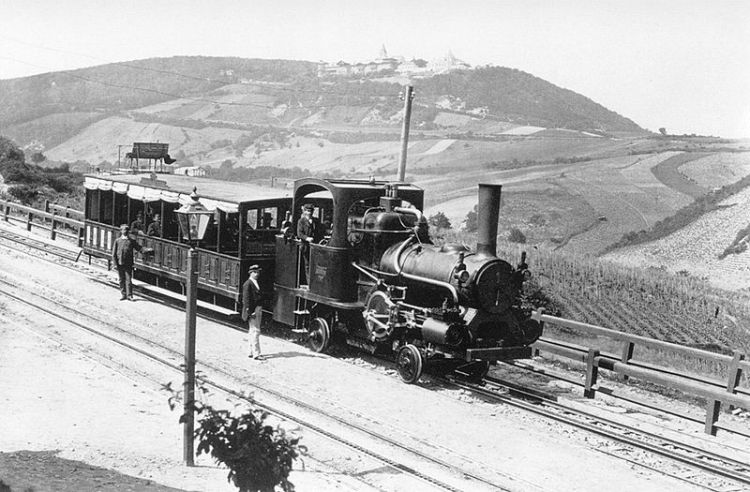 Die Kahlenbergbahn in der Station Grinzing, 1875. Im Hintergrund der Kahlenberg (484m) mit dem alten Hotel, der Kirche St. Josef und der Malervilla.